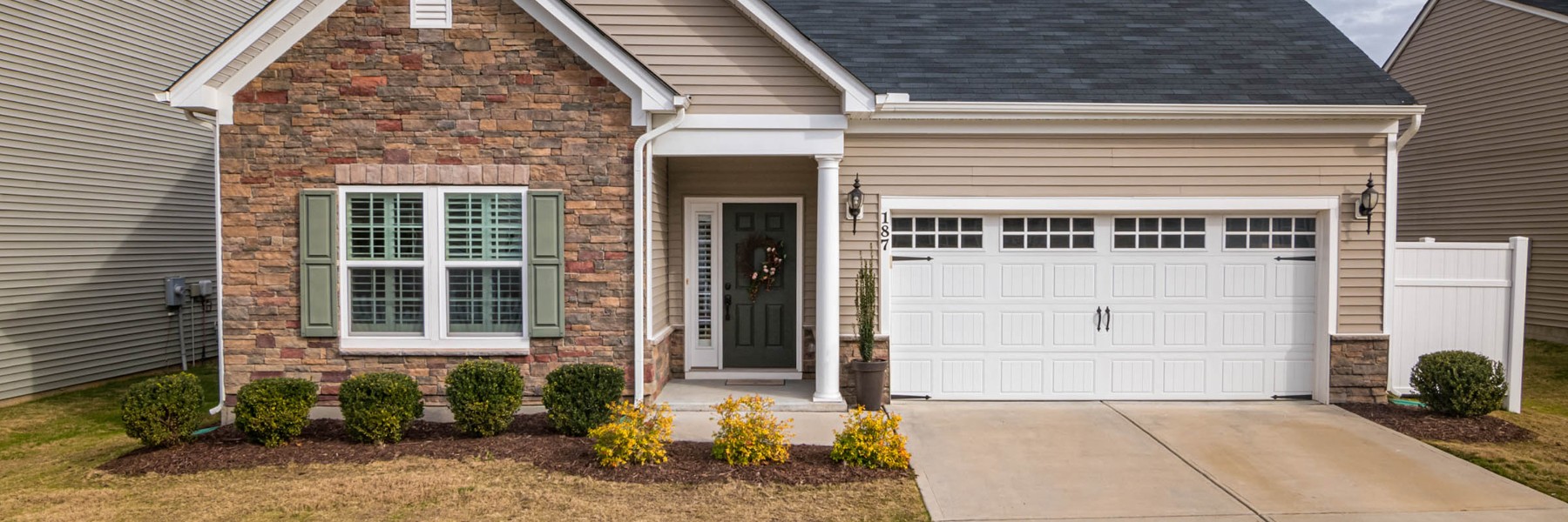 Home exterior with stone veneer, tan siding and a dark shingle roof
