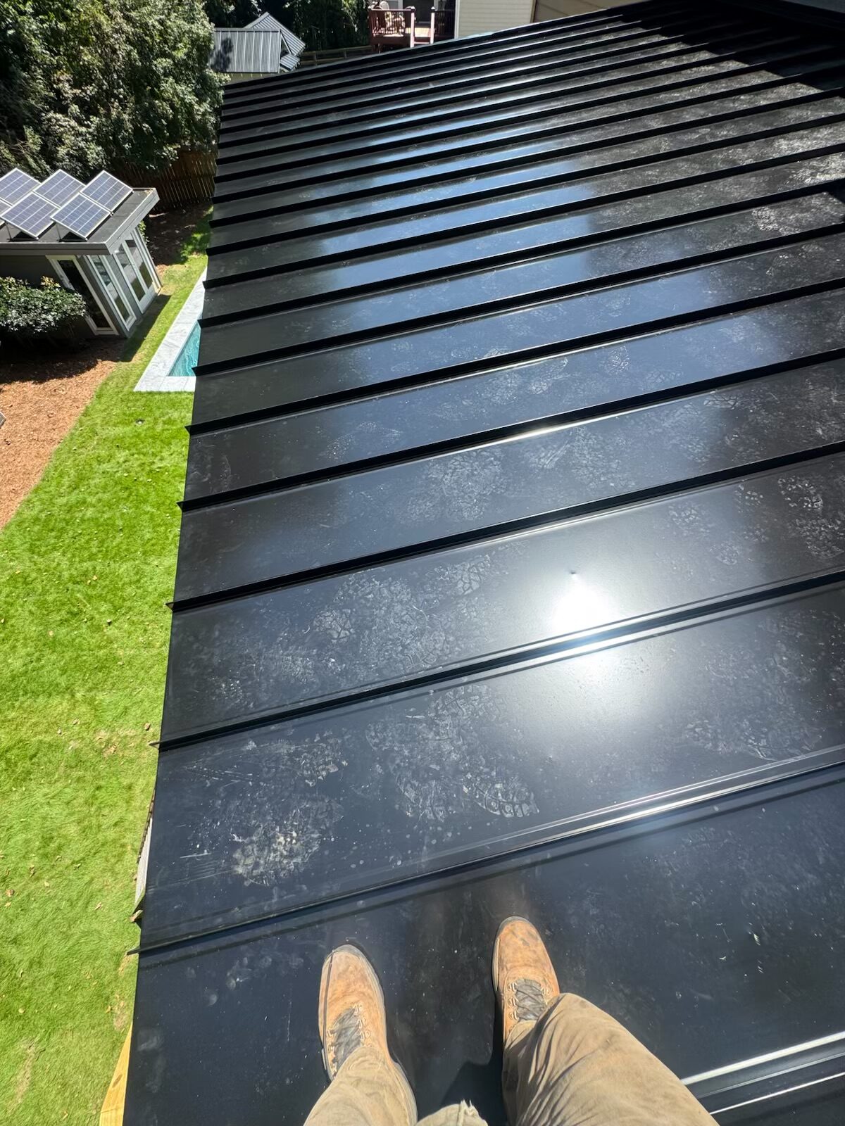Black standing seam metal roof installed over a backyard