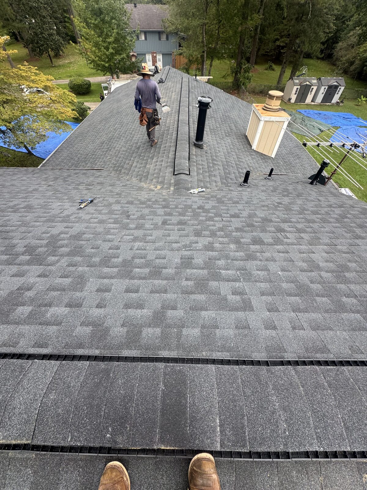 Roofer finishing a new gray architectural shingle roof